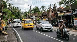 Busy Bali street with mixed vehicles and blue taxi